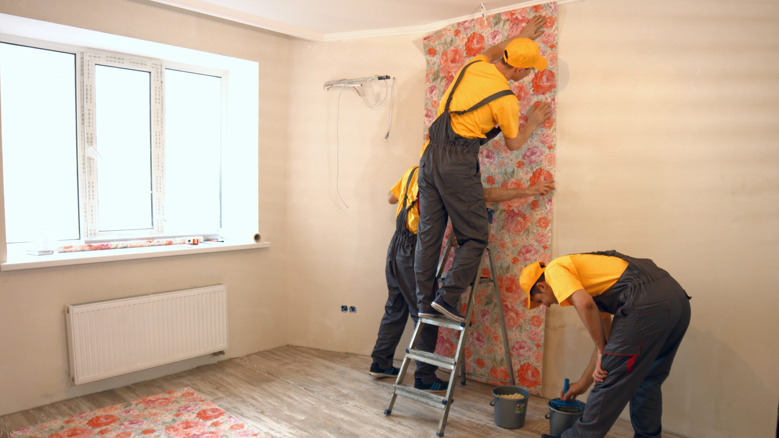Builders hanging wallpaper in new apartment. Builders hanging wallpaper in new apartment. Builders working together at construction area.