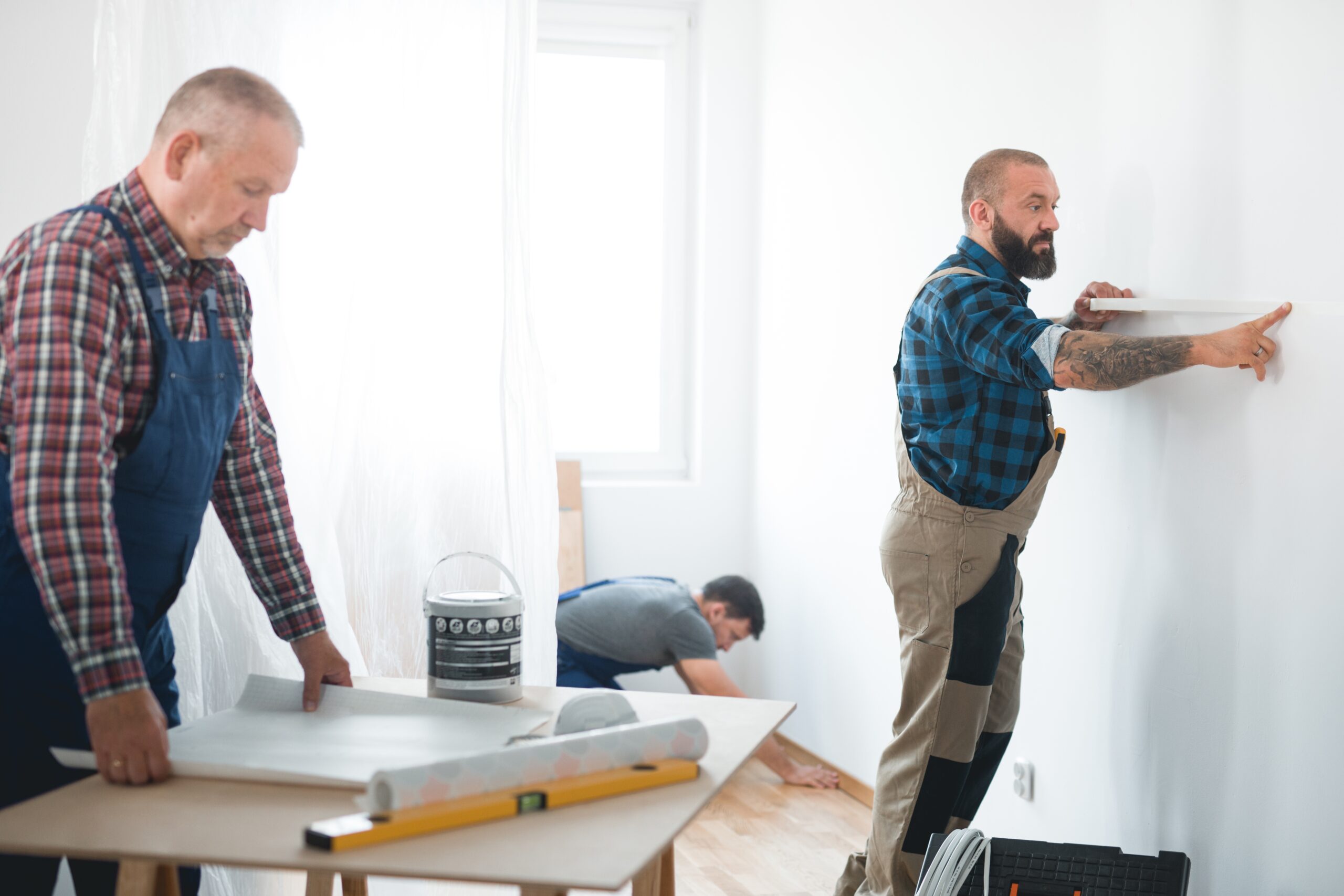Renovation crew of three professional builders remodeling bright apartment