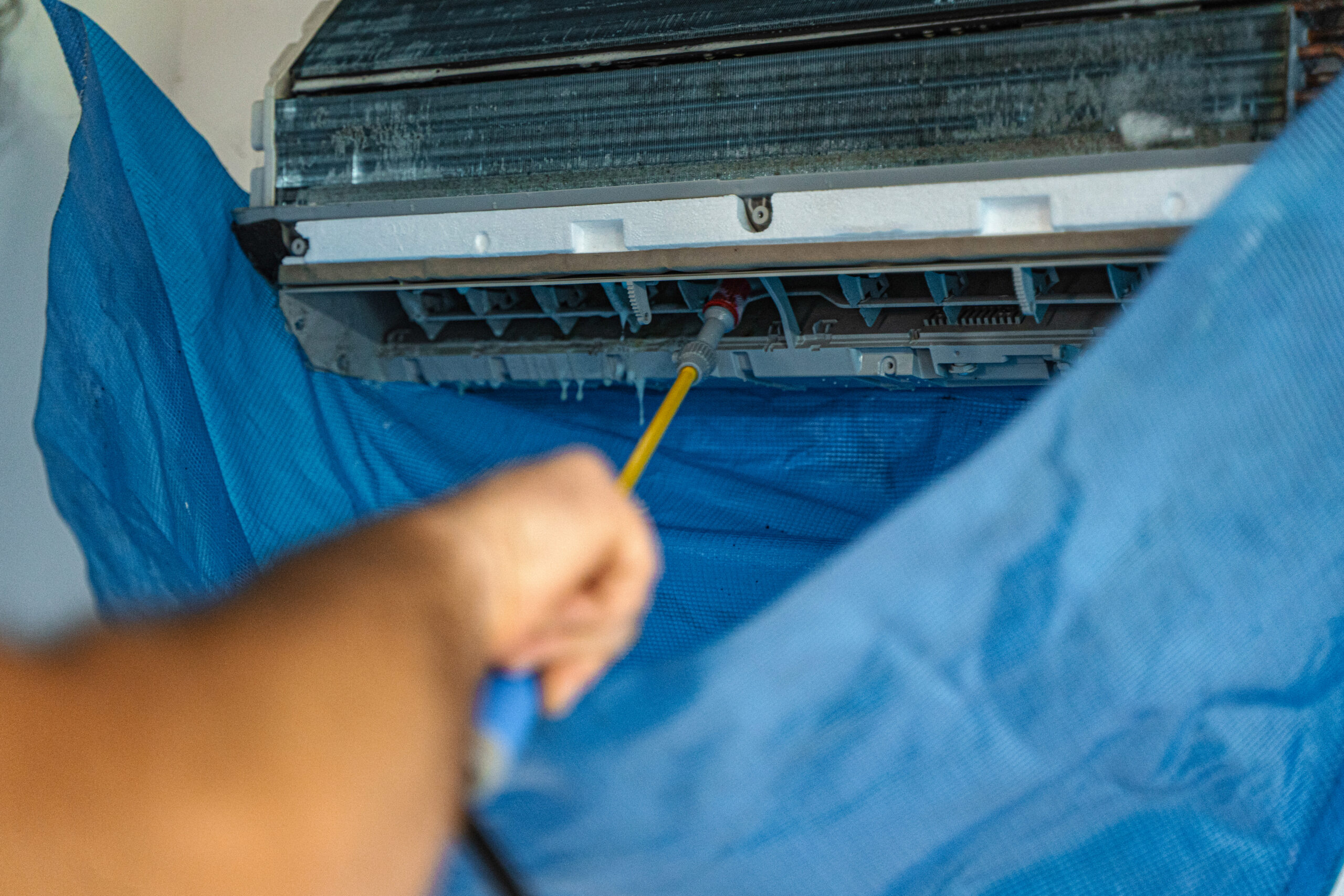 The technician are cleaning the air conditioner by spraying water.